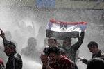 En egyptisk demonstrant holder det egyptiske flag op foran politistyrker, der bruger vandkanoner mod demonstranterne i Kairo. 