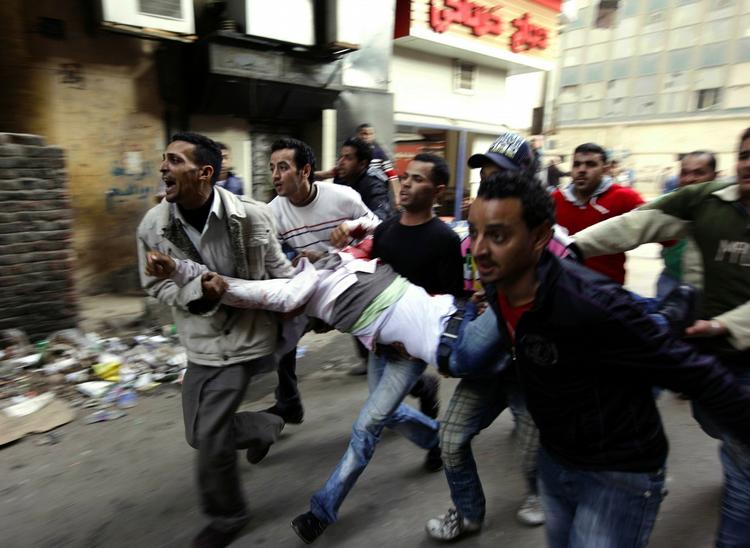 Demonstrationer. Egyptere bærer en såret mand væk efter et sammenstød med urobetjente i Kairo. 