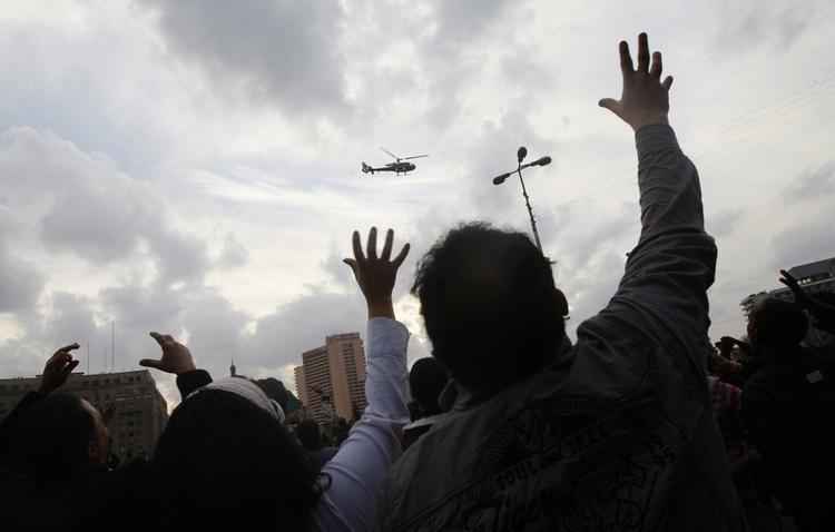 Sammenhold. Demonstranter i Kairo vinker mod en militærhelikopter, der sammen med flere fly viste sig over byen umiddelbart inden aftenens udgangsforbud trådte i kraft. 