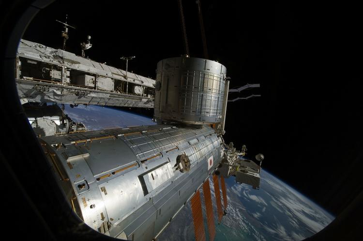 Perspektiv. Jorden ses bag den internationale rumstation. Billedet er taget af en astronaut, der her befinder sig på rumfærgen Atlantis. 