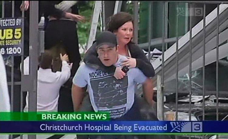 En skrækslagen kvinde bæres væk fra en beskadiget bygning. 