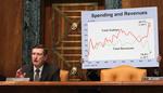 Underskudsforretning. Formanden for senatets budgetkommite, Kent Conrad, fotograferet i januar foran en planche, der viser det voksende hul mellem udgifter (den røde kurve) og indtægter i amerikansk økonomi. 
