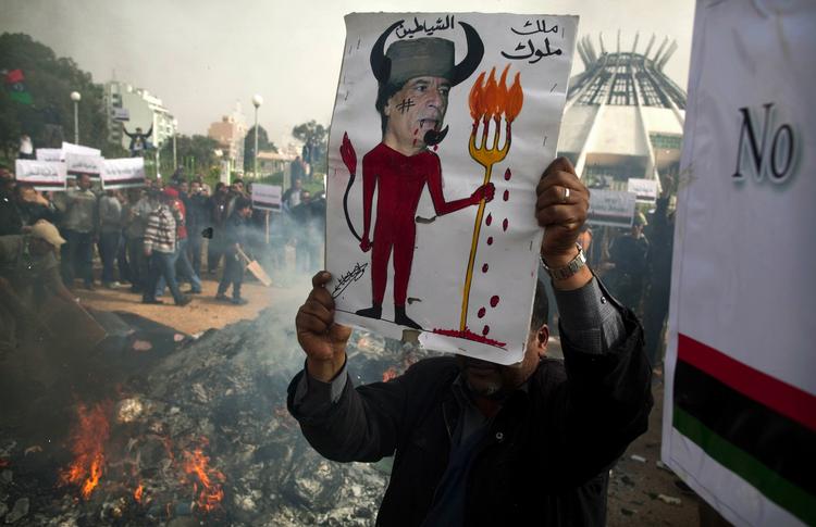 En demonstrant holder en plakat med Gaddafi, mens hans 'Grønne bøger' afbrændes i baggrunden. 