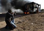 En oprørssoldat skyder mod en brændende bil tilhørende styrker tro mod Gaddafi nær byen Brega, i den østlige del af Libyen. 