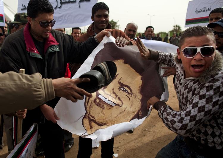 Demonstranter slor med sko på en plakat med Gaddafi ved en demonstration i Bengazi. 