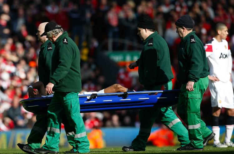 ude. Manchester Uniteds Nani bæres fra banen efter tacklingen af Liverpools Jamie Carragher. 