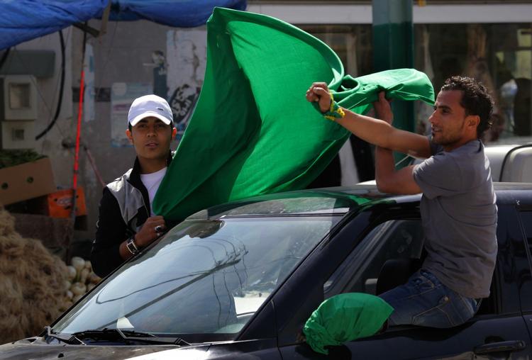 Gaddafi-land. Her holder støtter af Gaddafi et grønt flag op, da de møder et hold udenlandske journalister i byen Janzour, der ligger 12 kilometer uden for hovedstaden. 