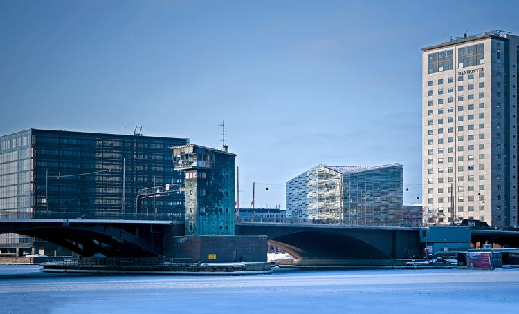 Tilpasset. Krystallen er et barn af sine omgivelser. Den ses her mellem  Nykredits store sorte glaskube og  Danhostels højhus med Langebros tårn i forgrunden. 