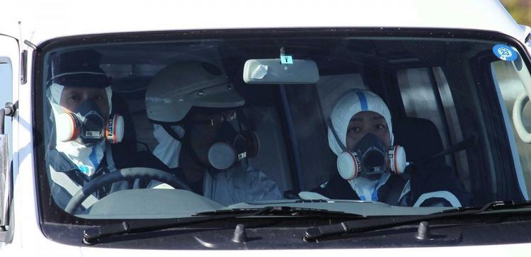 Foranstaltning. Politifolk iført sikkerhedsudstyr, mens de kører i området tæt på Fukushima-stomkraftværket. 