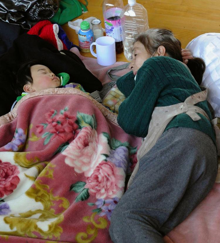 evakueret. En bedstemor betragter sit sovende barnebarn i et midlertidigt evakueringscenter i Otsuchicho i Iwate-distriktet i det nordlige Japan. 