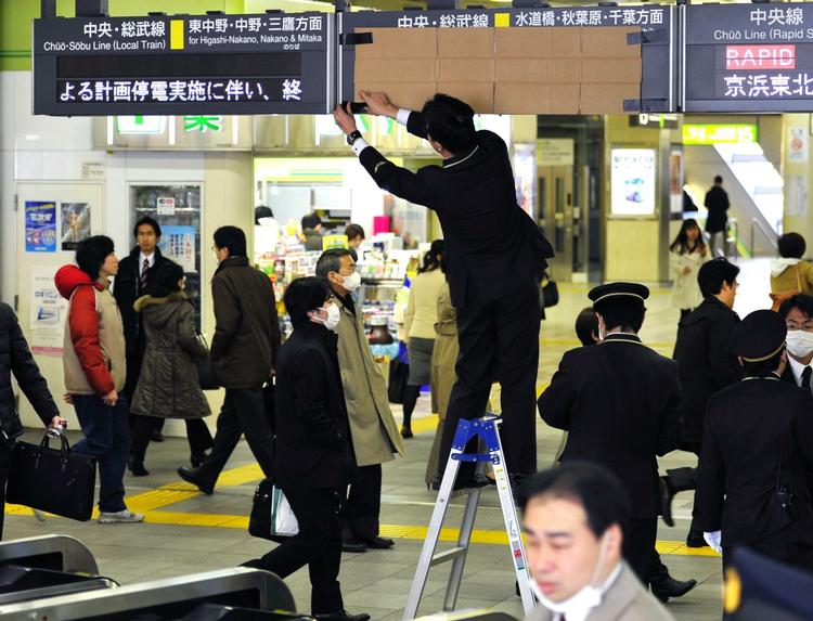 Aflyst. En stationsmedarbejder dækker et skilt til, efter at det er blevet besluttet at aflyse forskellige togafgange i Tokyo som følge af problemerne med strømforsyningen. 