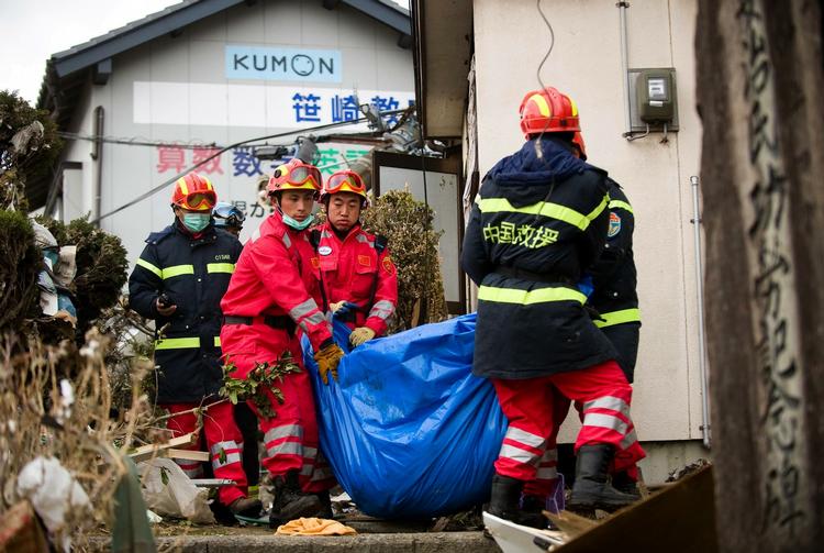 Redningsarbejde. Kinesiske redningsarbejdere i byen Ofunato fjerner liget af et af ofrene fra jordskælvet, som fredag ramte Japan med en enormstyrke på 9,0 på richterskalaen. 