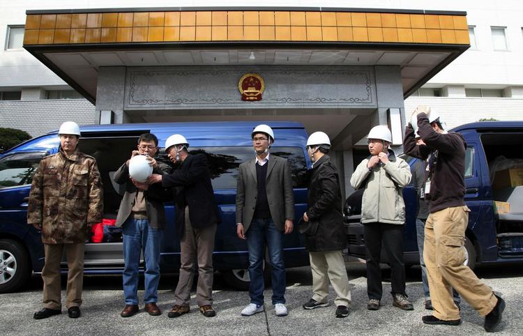 Afgang. Det er især kinesere og sydkoreanere, der arbejder i Japan, som står i kø for at komme ud af landet. Her venter en gruppe ansatte på den kinesiske ambassade på at komme væk. 