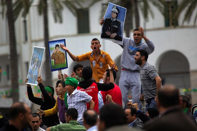 DØDVANDE. I Libyen fejrer Gaddafi-tilhængere efter at have fået at vide, at Gaddafis styrker har generobret endnu en by, mens borgere over hele verden fortvivles over dødvande i forhandlingerne om et flyveforbud. 