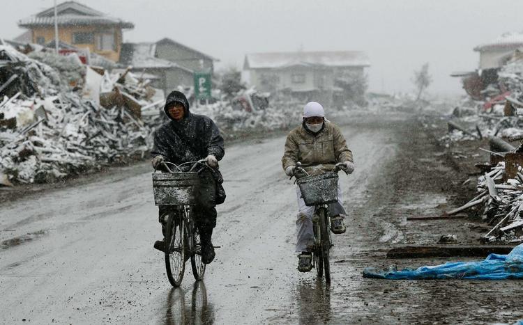 To cyklister på vej gennem ruinerne i Natori. 