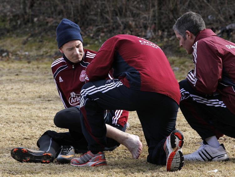 av. Søren Kaalund (med ryggen til) og Johannes Breum tog Nicklas Bendtner under behandling efter forvridningen af venstre ankel. 