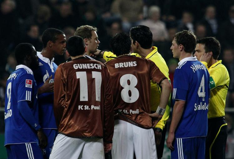 afbrudt. Spillerne flokkes om dommeren, da kampen mellem Schalke 04 og St. Pauli blev afbrudt to minutter før tid. 