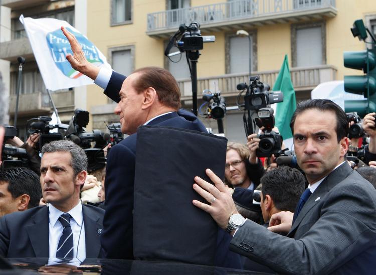 SILVIO. Berlusconi er involveret i fire retssager for tiden. Sidste mandag var han i retten i Milano anklaget for skattesvig. Her beskytter en sikkerhedsvagt hans ryg da han forlader retten, mens Berlusconi hilser på pressen. 