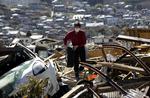 Overlevende. Keichi Kudo finder et bildæk i ruinerne efter jordskælvet i Japan. 28.000 meldes dræbt eller savnet som følge af skælvet og den efterfølgende tsunami. 