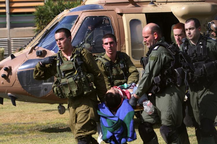 Gaza. Israelske soldater hjælper en passager fra skolebussen, der blev ramt af et morterangreb. 