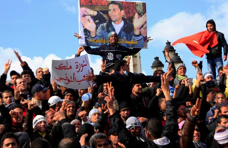 Symbol. Tunesere demonstrerer under en plakat med et billede af frugtsælgeren Mohamed Bouazizi, der døde efter at have sat ild til sig selv. 