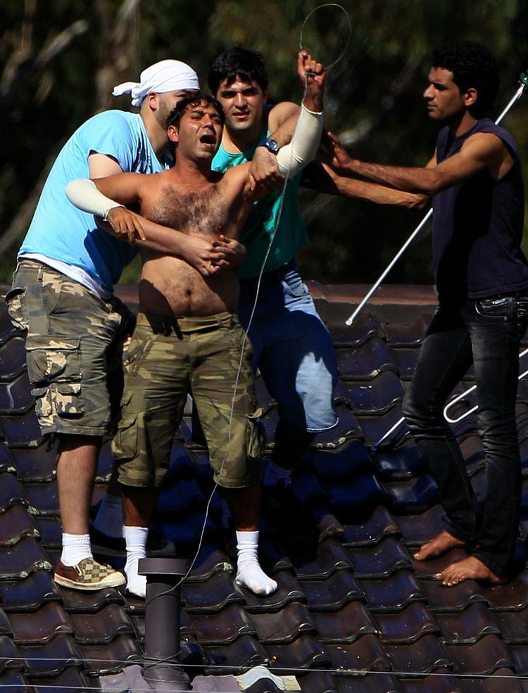 Nødråb. En asylsøger på Villawood i Sydney truede med at hoppe ud fra taget på en bygning på asylcentret, men det lykkedes andre at få forhindret ham i det. 