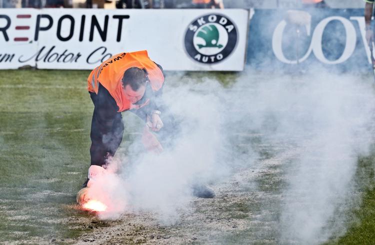 Pyroteknik. Romerlys er hverdag i dansk fodbold. Her er en Lyngby-kontrollør - han har intet med sagen i Herning at gøre -  ved at fjerne fyrværkeri i forbindelse med kampen mod FCK skærtorsdag. 