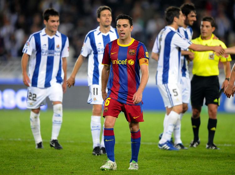 slapt. En skuffet Xavi fra Barcelona går fra banen, mens jublende Real Sociedad-spillere nyder sejren over mesterholdet. 