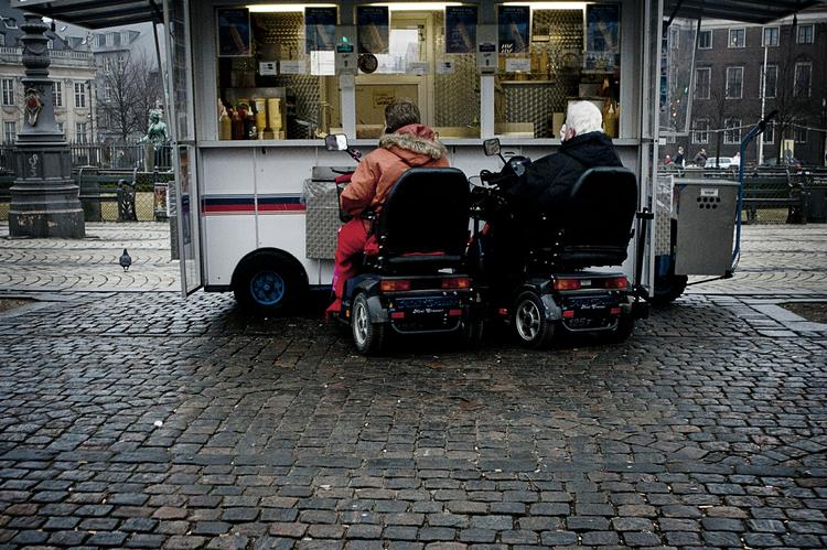 Københavner-odyssé. Journalistpraktikant Emil Bergløv og fotografpraktikant Martin Lyngstad Slottemo har været på en tre-dages jagt efter Københavns egenart. Her ses to ældre mennesker i handicap-knallerter, mens de nyder en pølse i en pølsevogn på Kgs. Nytorv. Alle fotos:  Martin Slottemo Lyngstad 