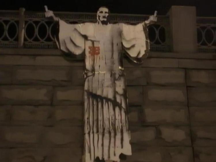 BLASFEMI. Denne plakat af Jesus med skråt op-fingre har fået en 24-årig russisk kunster fængslet. Man må ikke lade frelseren sådan 'flip the bird', som amerikanerne kalder den åbenbart uhellige handling. 
