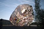 Genbrug. På Roskilde Festival skal publikum hjælpe kunstnerkollektivet Museo Aero Solar med at bygge en kæmpeballon af gamle plastikposer. Ballonen pustes op ved hjælp af ventilatorer og begynder at svæve, når solen har varmet luften op. 