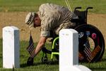 Sorg. Arlingtong kirkegården i Washington i går. Lance Cpl. Brandon Long, der selv blev såret i Afghanistan, sætter et flag ved gravstenen hos en kammerat, som ikke klarede den. 