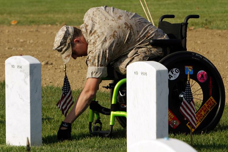 Sorg. Arlingtong kirkegården i Washington i går. Lance Cpl. Brandon Long, der selv blev såret i Afghanistan, sætter et flag ved gravstenen hos en kammerat, som ikke klarede den. 