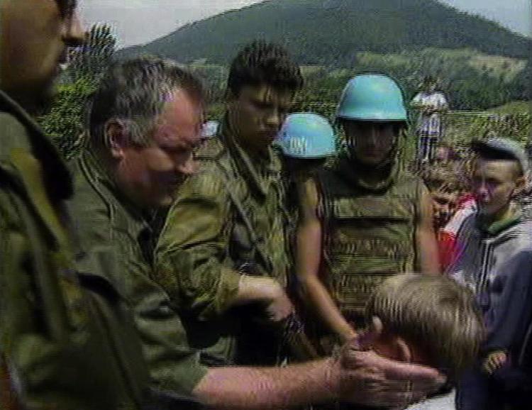 General Ratko Mladic klapper en muslimsk dreng på hovedet, inden han henvender sig til den muslimske befolkning i den bosniske by Srebrenica d. 12 juli 1995. Kort efter trak FN sig og serberne gik i gang med at myrde drenge og mænd fra byen, FN havde udråbt til en 'sikker zone' for de mange flygtninge fra krigen. 