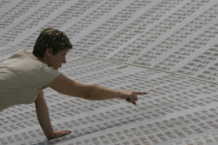 En muslimsk kvinde kigger efter en pårørendes navn på det store mindesmærke med de 8,370 navne efter massakren i Srebrenica. 