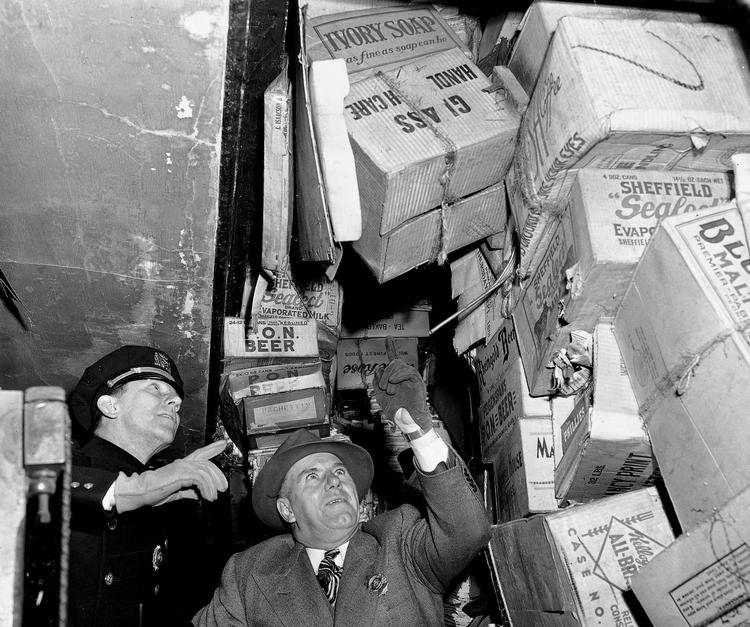 fælde. To politifolk undersøger brødrene Collyers hus i Harlem i 1947, hvor der blandt andet var konstrueret skjulte fælder af de mange ton bøger og aviser. Nu har E.L. Doctorow skrevet en roman inspireret af brødrenes excentriske liv. Arkivfoto: Anthony Camerano/AP 