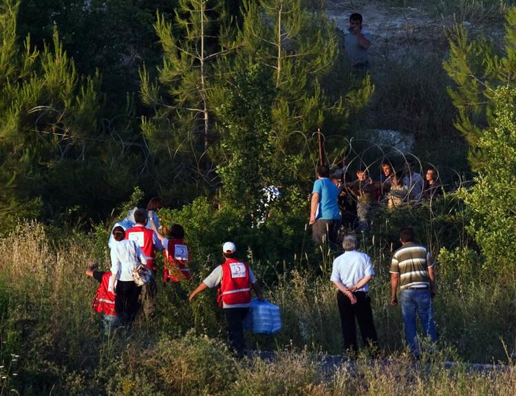Assistance. Tyrkiske Røde Halvmåne-medarbejdere kommer med mad til syriske flygtninge, der venter på den syriske side af grænsen nær den tyrkiske landsby Guvecci i Hatay-provinsen. 