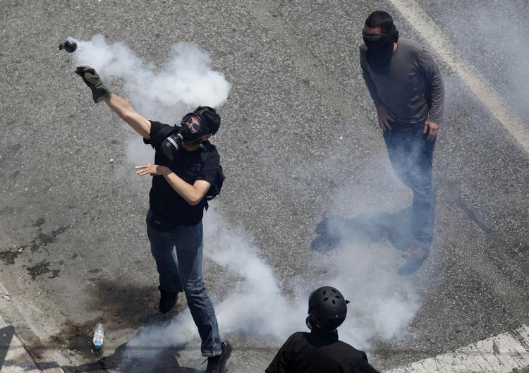 Retur. Demonstranter kaster tåregasgranater tilbage til politiet under dagens demonstrationer i Athen. 