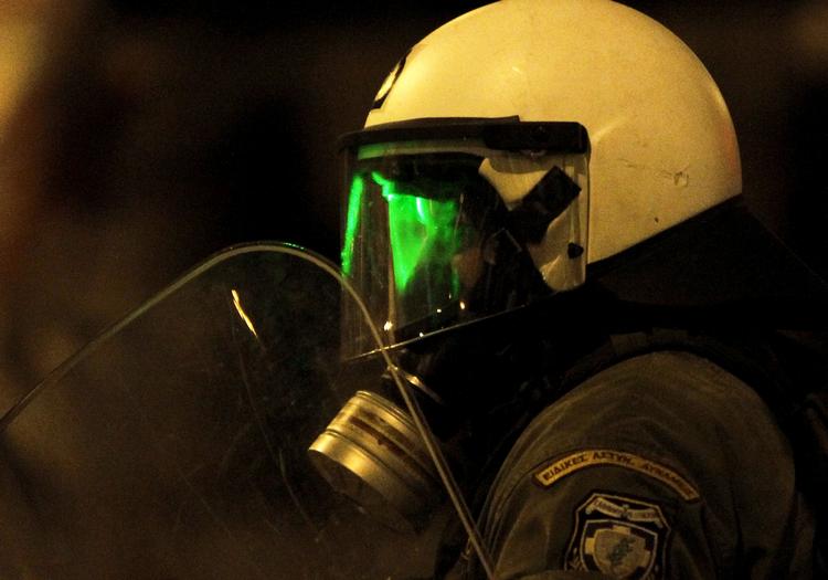 Demonstranter prøver af blinde en urobetjent med en laserlygte. 