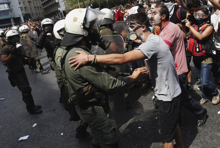 Urobetjente og demonstranter ser hinanden an i Athens gader. 