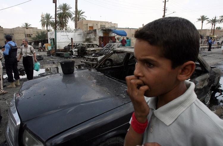 Krig. En irakisk dreng iagttager situationen umiddelbart efter en bilbombe har dræbt tre og særet to i Bagdad i 2007. 