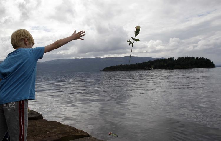sorg. En dreng smider en rose i vandet ud for øen Utøya. 