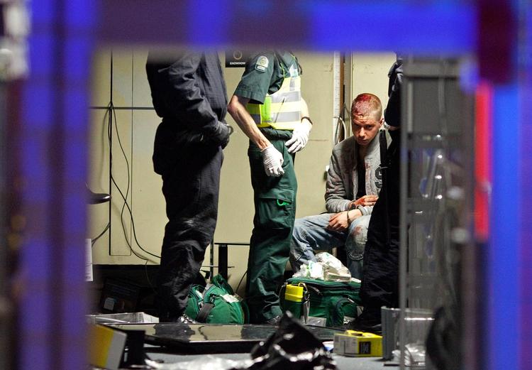 En såret mand behandles i en ambulance efter at være blevet arresteret for butikstyveri. 