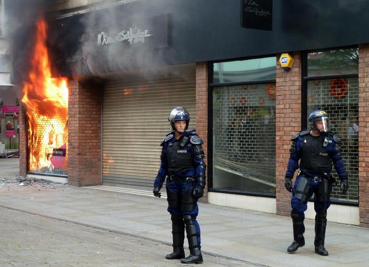 OPTØJER. Betjente i kampuniform foran brændende butik i Manchester. 