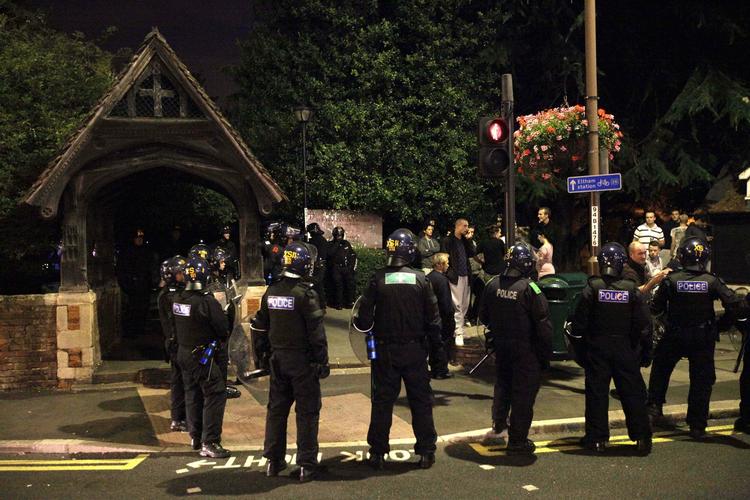 Konfrontation. Politi har for at forebygge uroligheder omringet en gruppe personer foran en kirke i London-bydelen Eltham. 