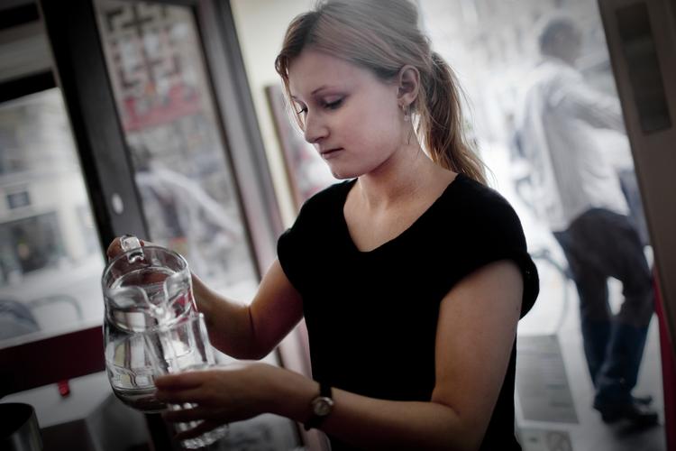 Tørstig. Karen Sofie Tøjner, tjener på Cafe Bjørg's, i færd med at hælde vand op til kunderne i går. Cafeen ligger uden for det område, som Københavns Kommune i dag har udpeget som kog vandet-område. 