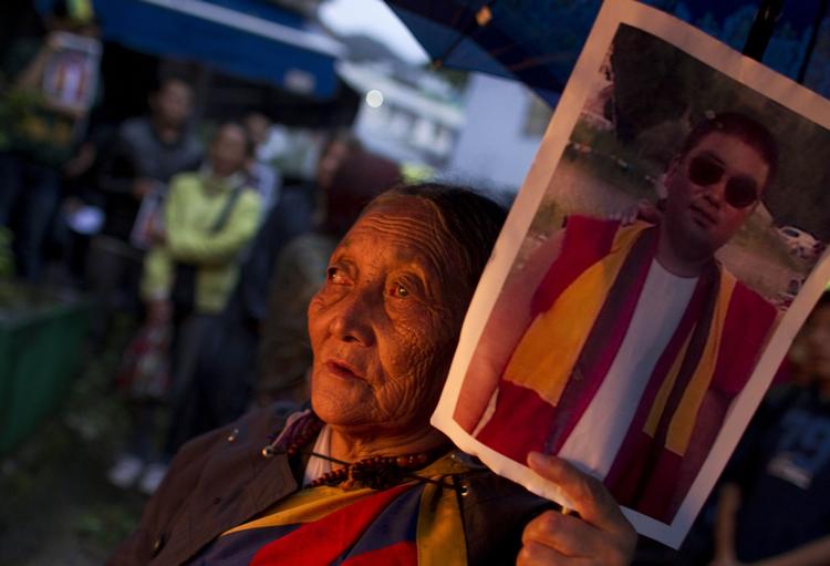 Protester. En eksiltibetaner holder et portræt af den munk, der døde 15. august af en selvafbrænding. 