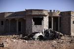 BYKAMP. Et ødelagt hjem i udkanten af Bani Walid. Foran står skroget af en bil med en anti-luftskytskanon påmonteret. 