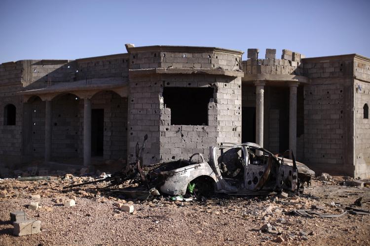 BYKAMP. Et ødelagt hjem i udkanten af Bani Walid. Foran står skroget af en bil med en anti-luftskytskanon påmonteret. 