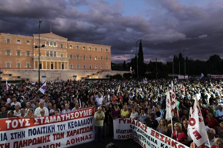 nedskæringer. Skyerne hang tungt over den græske parlamentsbygning i går, da regeringen vedtog yderligere nedskæringer i den offentlige sektor. Tusindvis af demonstranter fulgte med udenfor bygningen. 